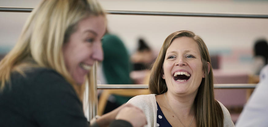 Two colleagues laughing over lunch